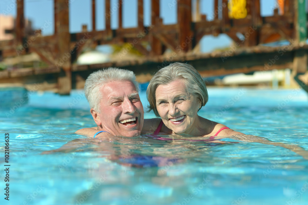 Wall mural Senior couple relaxing at pool