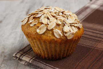 Fresh muffin with oatmeal baked with wholemeal flour on checkered tablecloth, delicious healthy dessert