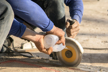 Arms worker with grinder cutting concrete