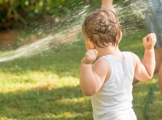 Child playing under sprinkler / hose on a hot day