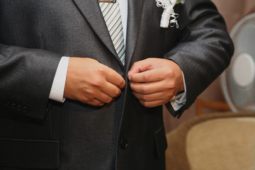 groom buttoning the buttons on the suit