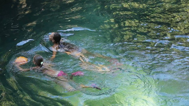 Young girls swimming in the beautiful mountain lake, enjoying a swim.Two girls are swimming in a mountain river in a canyon in the rainforest.Travel concept.Family,summer vacation.Adventure concept