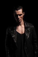 Fototapeta premium latin biker in black leather jacket posing in dark studio