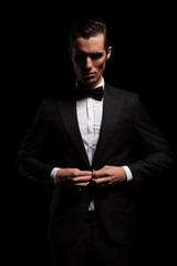 businessman in black toxedo with bowtie posing in dark studio