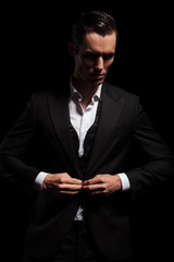 elegant man in black tuxedo posing in dark studio