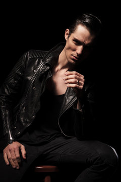 man in leather jacket posing seated while resting
