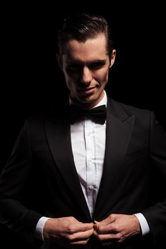 smiling elegant man posing in dark studio closing his jacket
