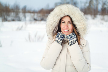 Christmas girl outdoor portrait. Woman in winter clothes on a snow field.