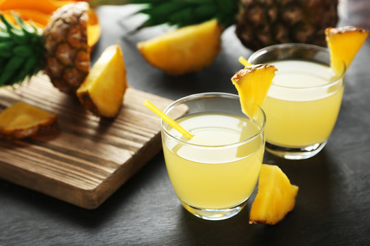 Glasses of pineapple juice on a black wooden table