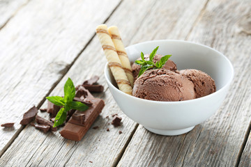 Sweet chocolate ice cream in bowl on grey wooden background
