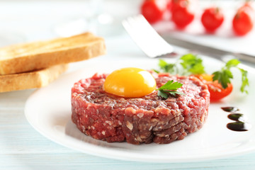 Beef tartare with egg yolk on a blue wooden table
