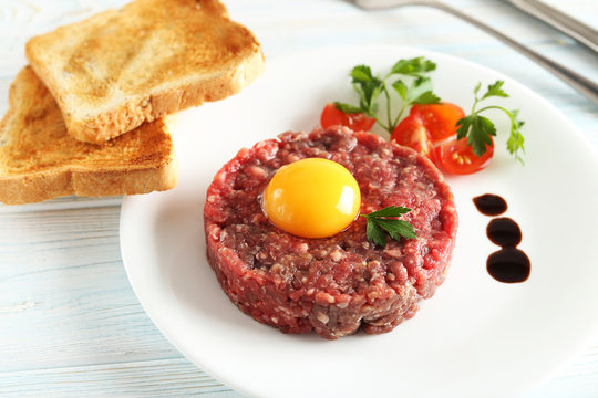 Beef tartare with egg yolk on a blue wooden table