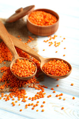 Red lentils in the wooden spoons on a blue wooden table