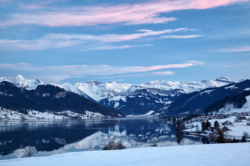 Winterliches Bergpanorama mit Sihlsee im Vordergrund, Spiegelungen im See, blaue Stunde