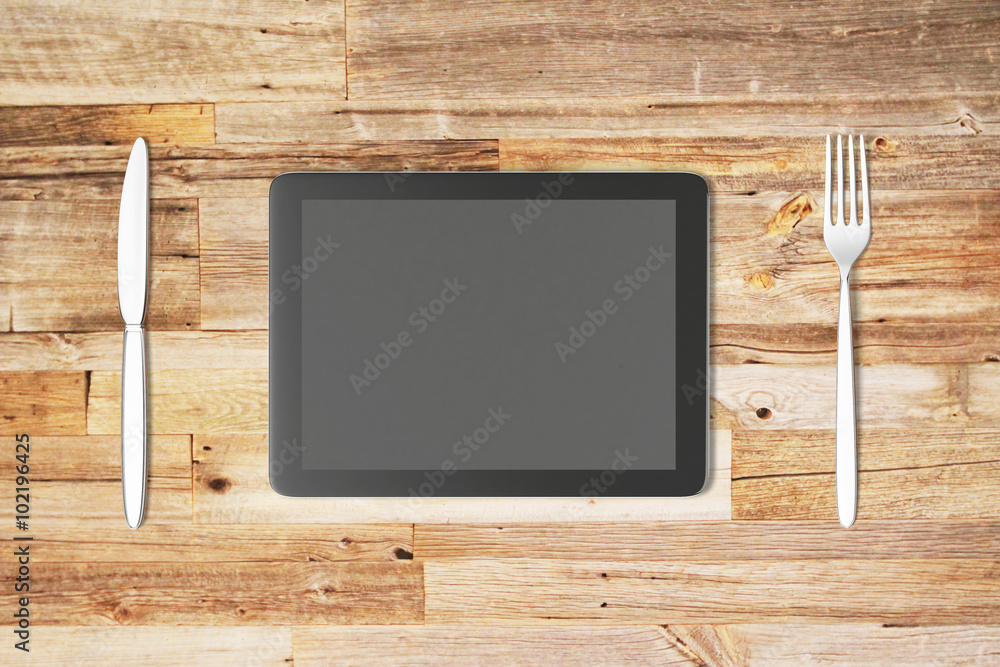 Poster digital tablet with fork and knife on a wooden table