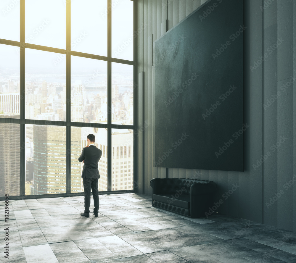 Poster Man stands near a window in a dark room with a blank a picture f