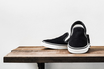 Still life with black slip-on casual shoes on wood table