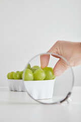 Magnified hand takes one grape