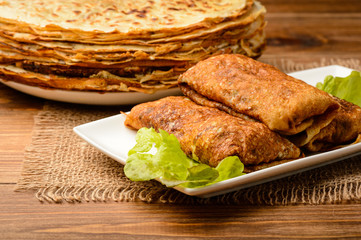 Stuffed pancakes on wooden background.