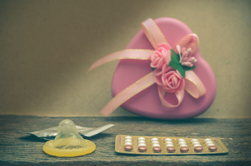 Condom and contraceptive pills on wood table