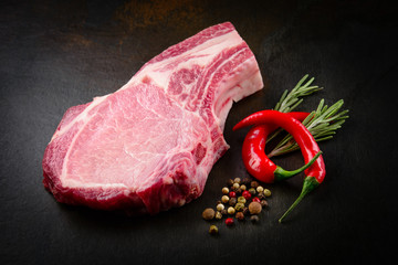 Slice of raw meat with spice on dark background. Organic food.