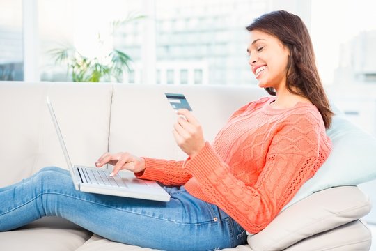 Smiling Woman With A Credit Card And A Laptop On A Sofa