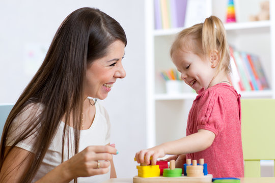 Cute woman and kid girl playing educational toys at home