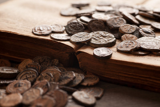 Pile of ancient coins on the very old book