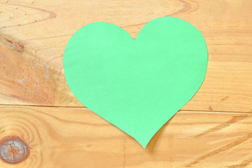 green heart made of paper on wooden background