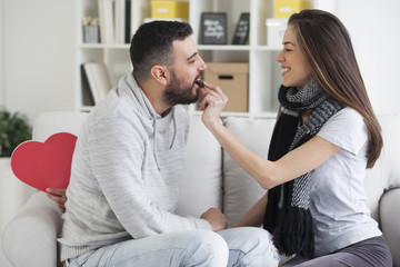 Valentines couple. Girl feeding her man with chocolate cookie,shallow depth of field