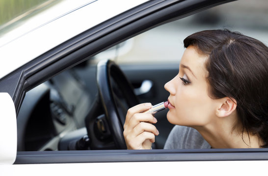 Pretty young woman in a car doing makeup