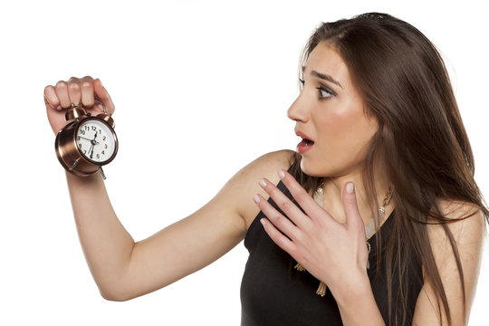 worried young woman holding alarm clock in her hand