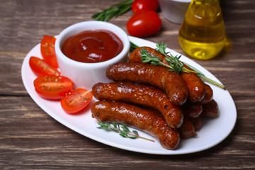 roasted sausages with tomato sauce and herbs on a wooden background