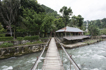 Fototapeta na wymiar Puente de madera sobre río en un pequeño pueblo en la jungla de de Sumatra, Indonesia