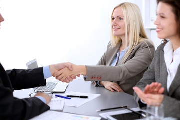 A group of business people at a meeting on the background of office. Business handshake. Focus on a beautiful blonde