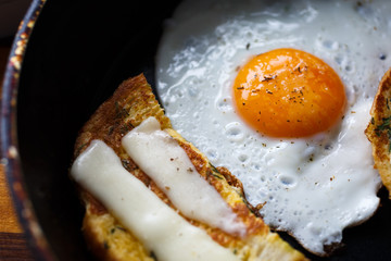fried egg and bread with cheese on the pan