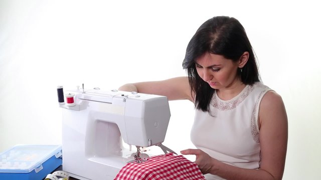 woman sews on the sewing machine 