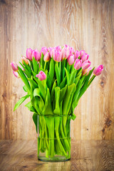 Tulips in the vase on wooden background