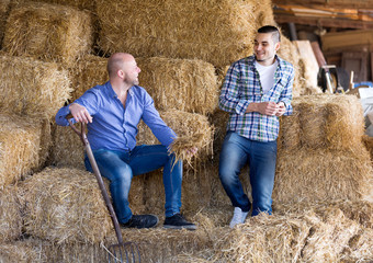 Naklejka na ściany i meble Two farm workers in hayloft