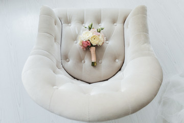 Beautiful wedding bouquet lying on a white armchair
