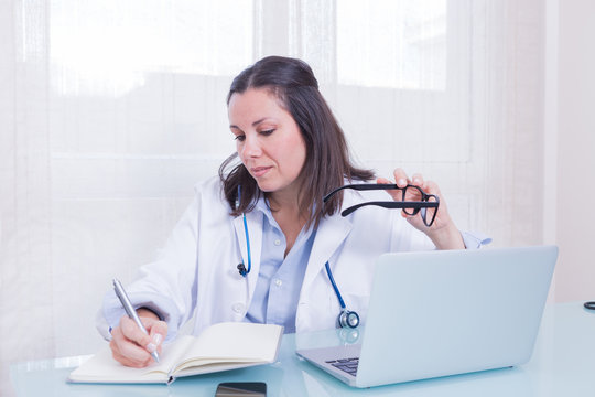 Portrait Of Busy Female Doctor At Table