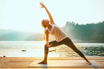 Yoga salutation au soleil. Jeune femme faisant du yoga au bord du lac, heure du coucher du soleil, image tonique