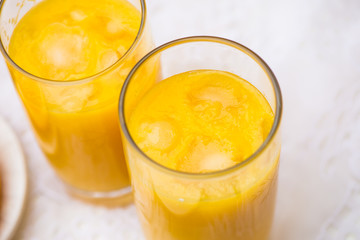 Two Glasses of Orange Juice with Ice on White