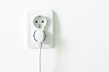 European white electrical outlet socket pluged in on white wall