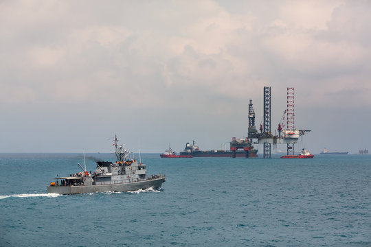 Image of oil platform and modern patrol vessel sailing in open sea