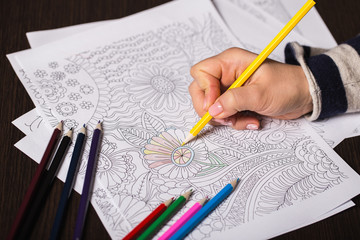 Girl paints a coloring book for adults with crayons - 102217817
