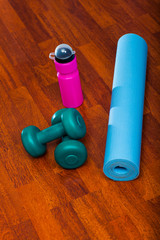 Two dumbbells with water bottle and yoga mat, sporty lifestyle concept