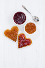 toasts in heart shape with fruit jam on white wooden background