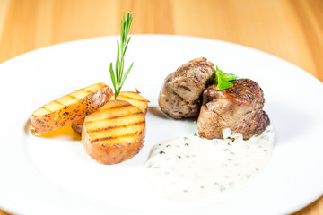 Beautiful juicy grilled meat with fried potatoes on a wooden table