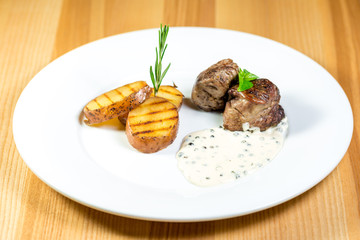 Beautiful juicy grilled meat with fried potatoes on a wooden table